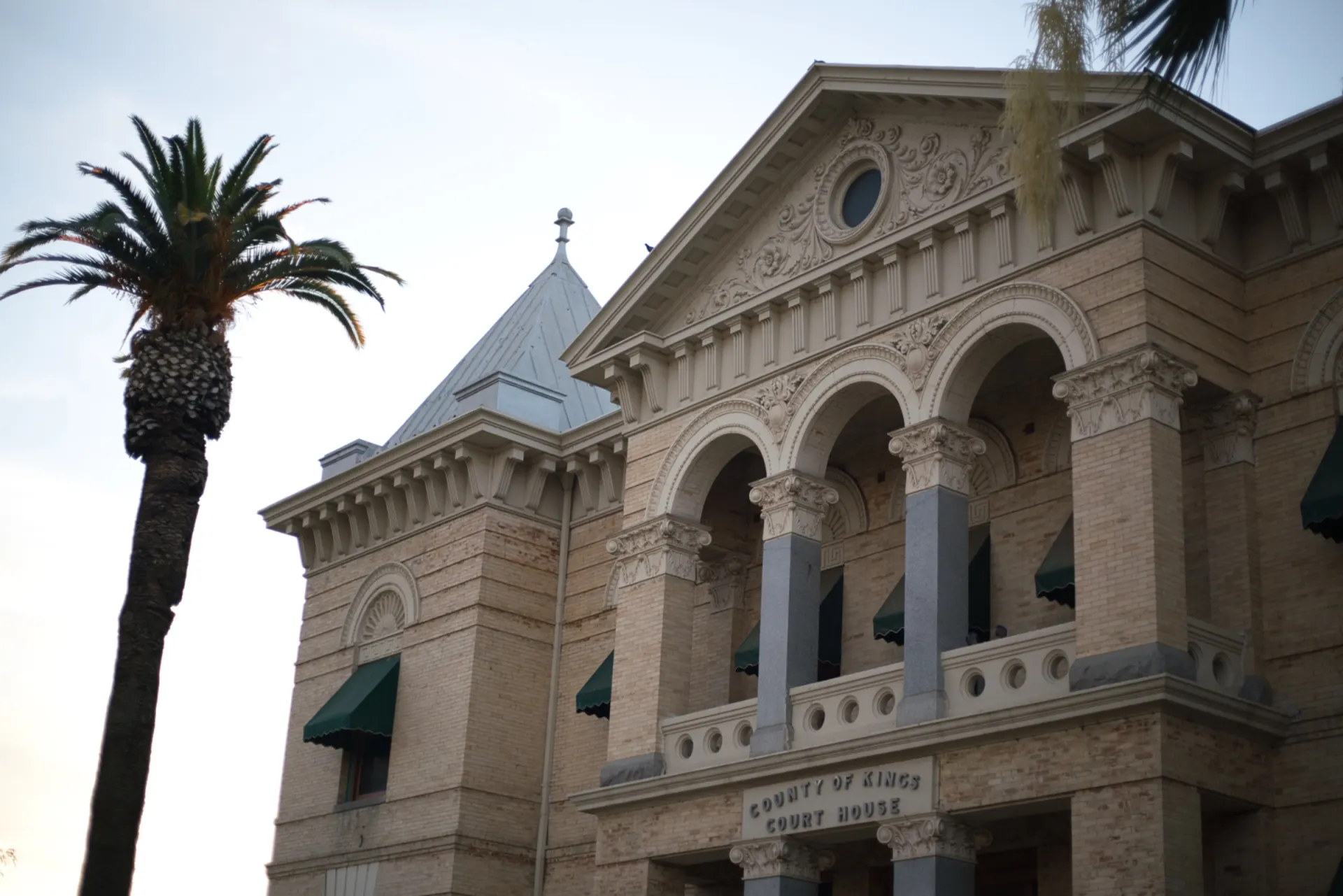 The historic County of Kings Court House in Hanford, California, its arcade and pediment seen from below at dusk